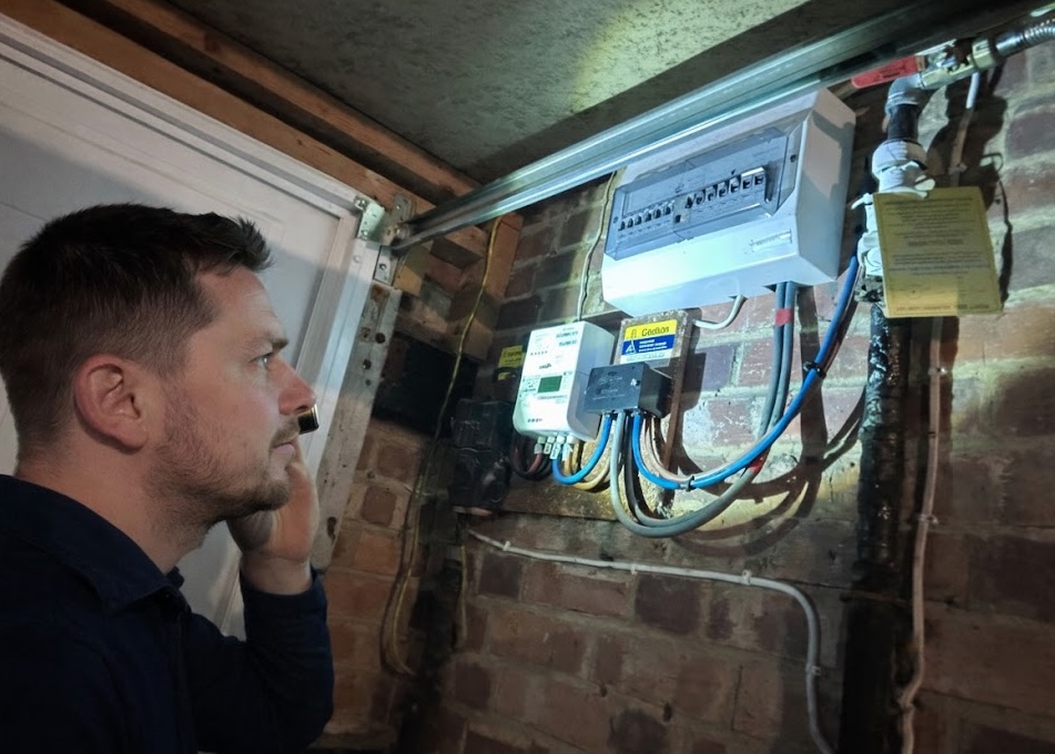 Electrician inspecting an external consumer unit on a brick wall